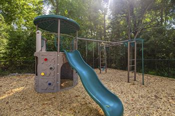 A playground with a green slide and a grey structure